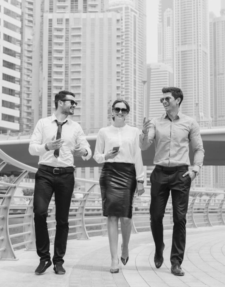 Three young professionals walking and talking in a cityscape.