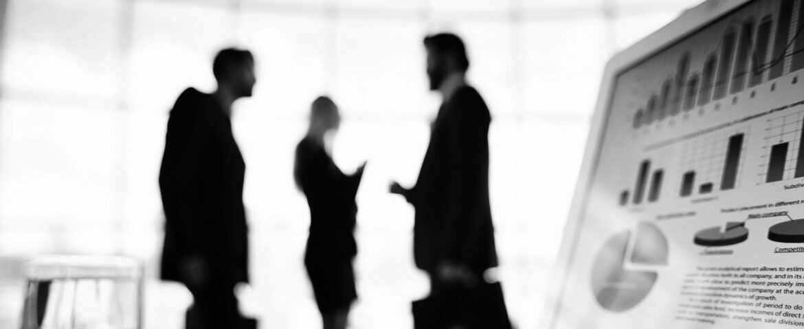 Silhouettes of three professionals engaged in conversation in a bright office space.