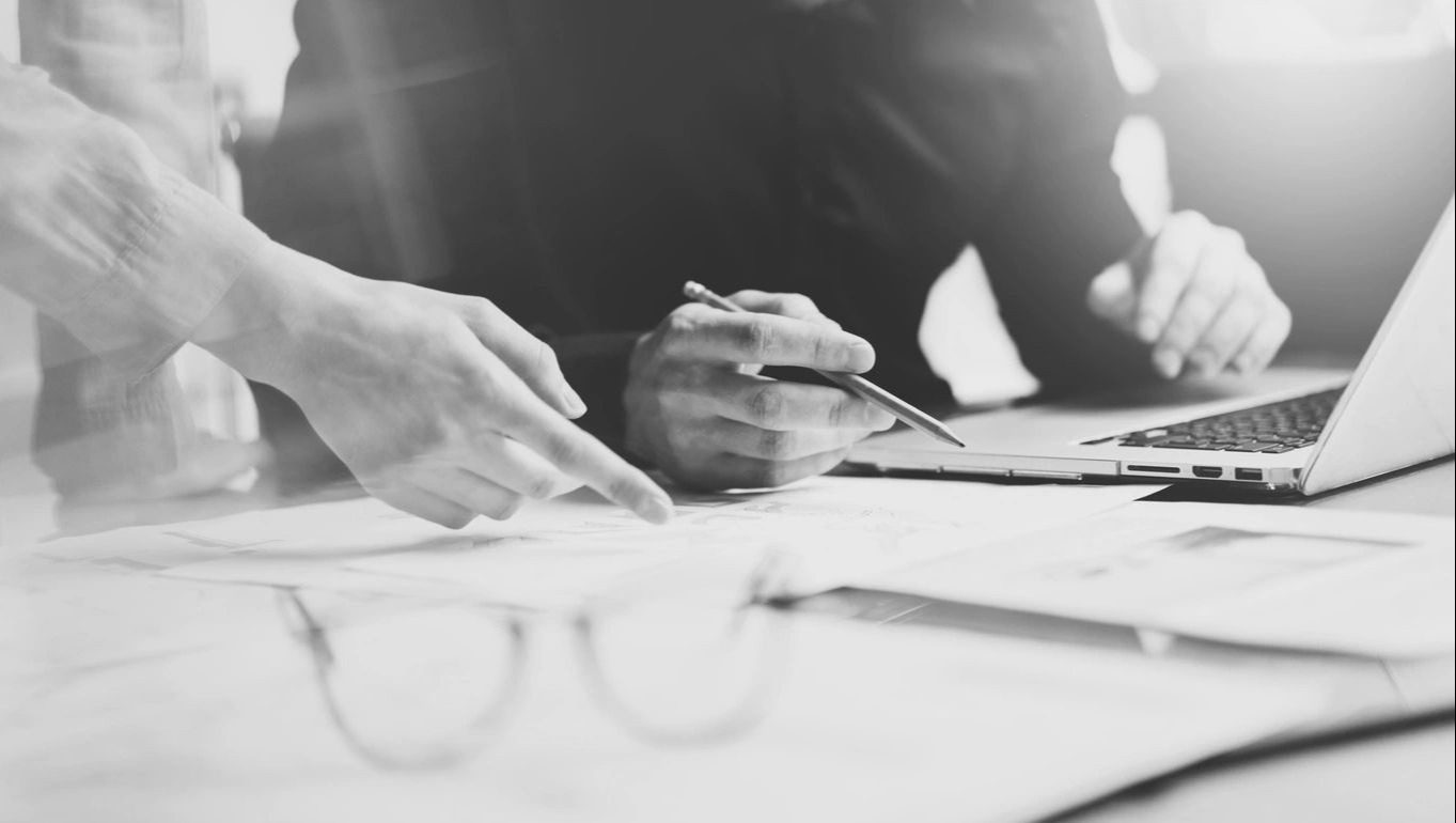 Two people collaborating over documents with a pen and clipboard.