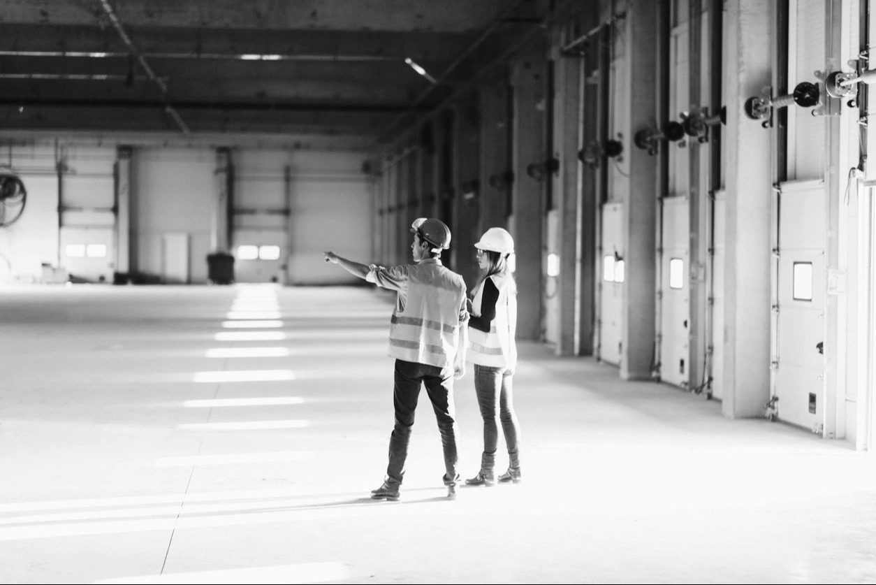 Two people walking in a spacious, industrial-style hallway.
