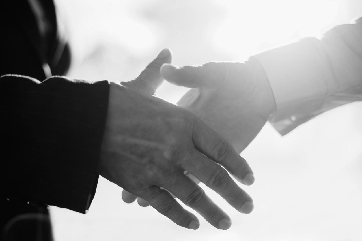 Two people shaking hands in a black and white photo.