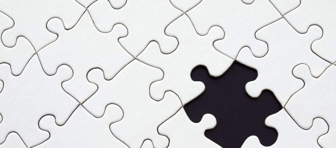 Close-up of a white puzzle with one piece missing.
